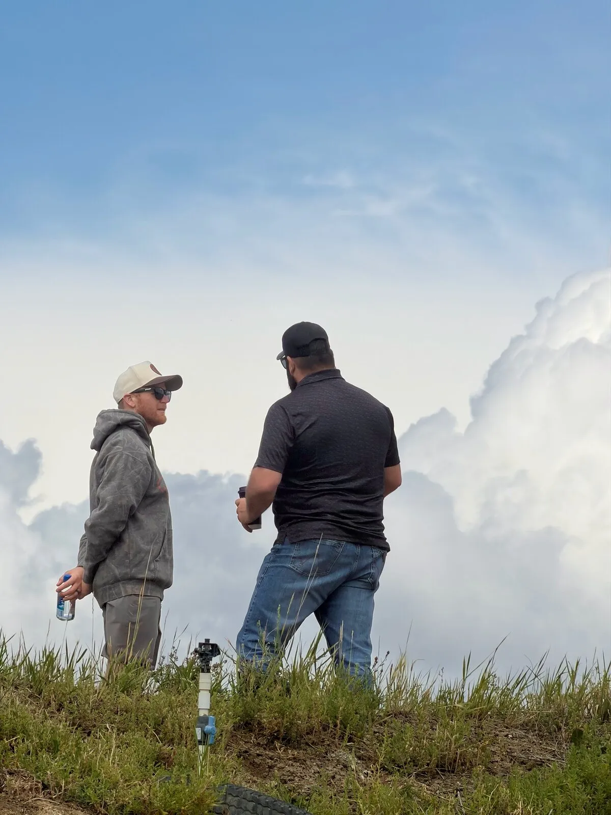Two men talking on a hillside under a big Montana sky