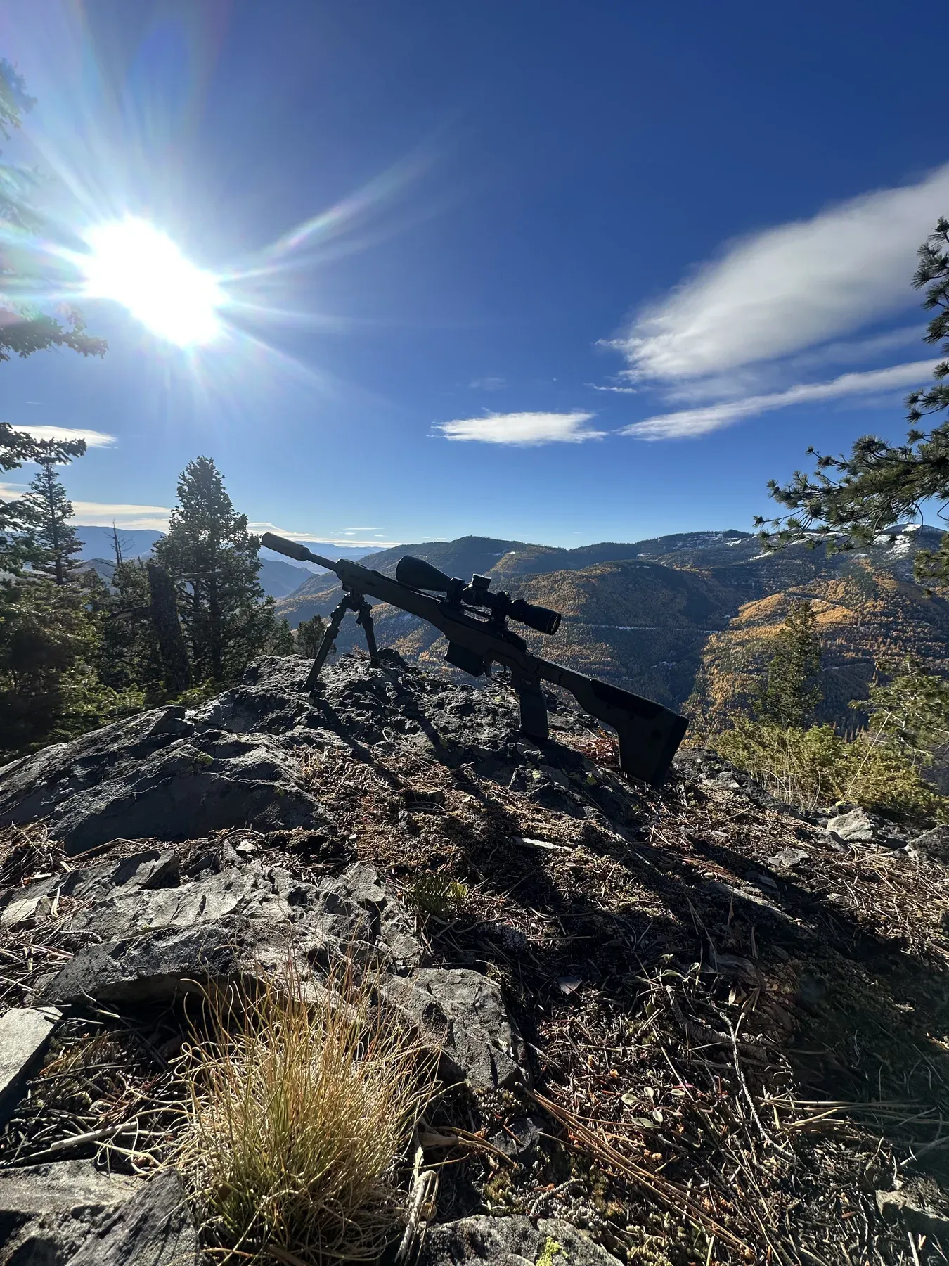 A rifle on a rocky ridge above a Montana valley